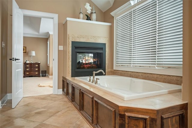 bathroom with a multi sided fireplace, vaulted ceiling, and a bathtub