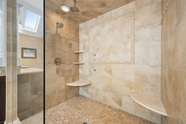 bathroom with a tile shower and a skylight