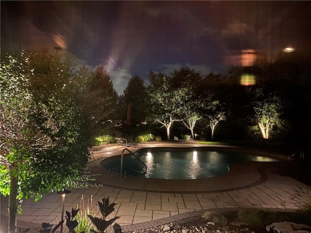 pool at twilight with a patio area