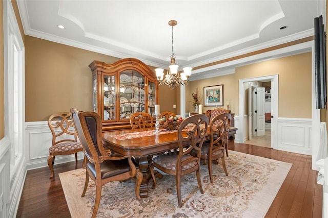 dining space with dark hardwood / wood-style floors, ornamental molding, a tray ceiling, and a notable chandelier