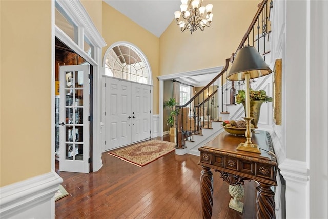 foyer entrance featuring lofted ceiling, dark hardwood / wood-style flooring, and a notable chandelier