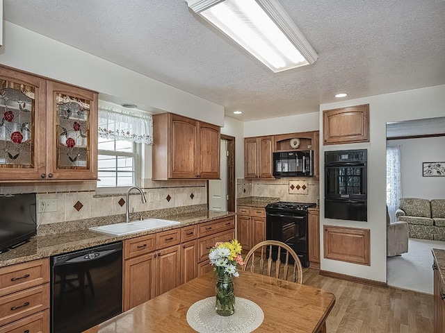 kitchen featuring sink, light hardwood / wood-style flooring, backsplash, black appliances, and a textured ceiling