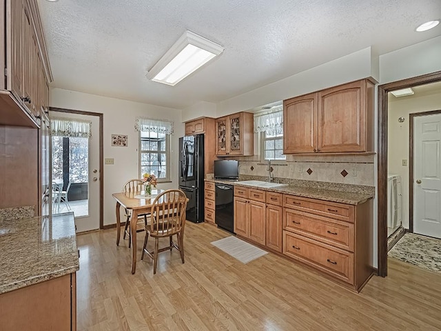 kitchen featuring backsplash, light stone countertops, a textured ceiling, and black appliances