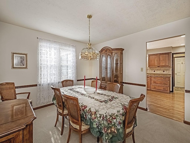 dining space featuring a notable chandelier, light carpet, and a textured ceiling