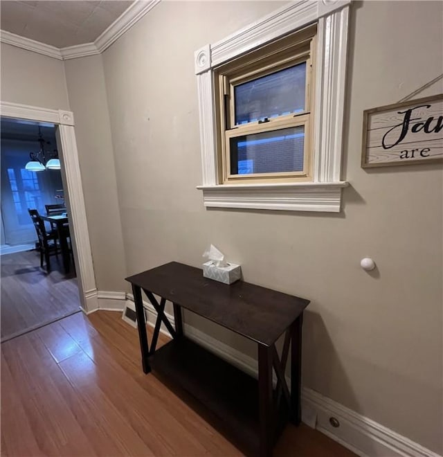 corridor with an inviting chandelier, crown molding, and hardwood / wood-style flooring