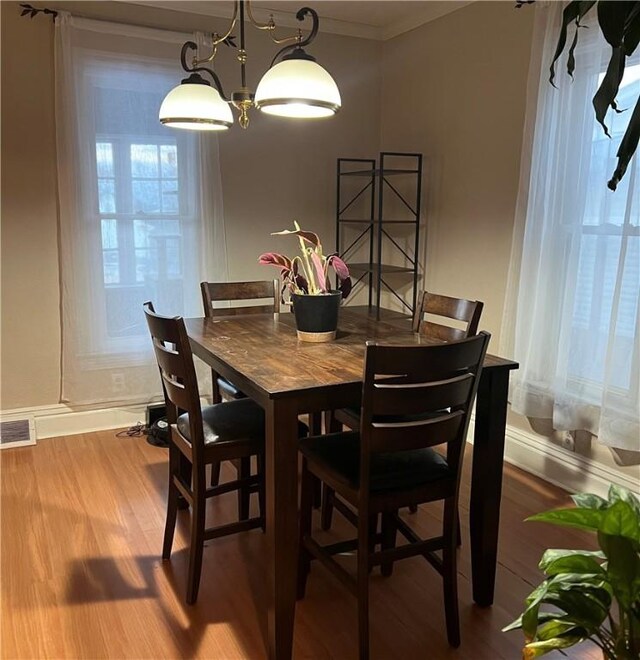 dining space featuring hardwood / wood-style flooring, ornamental molding, and an inviting chandelier