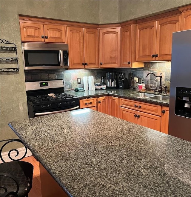 kitchen featuring appliances with stainless steel finishes, a kitchen breakfast bar, sink, and dark stone countertops