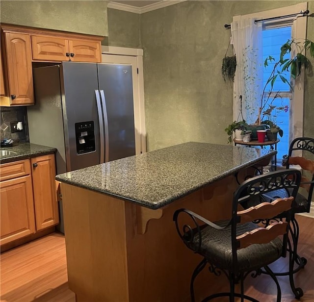 kitchen with ornamental molding, a kitchen breakfast bar, light hardwood / wood-style floors, and stainless steel fridge with ice dispenser