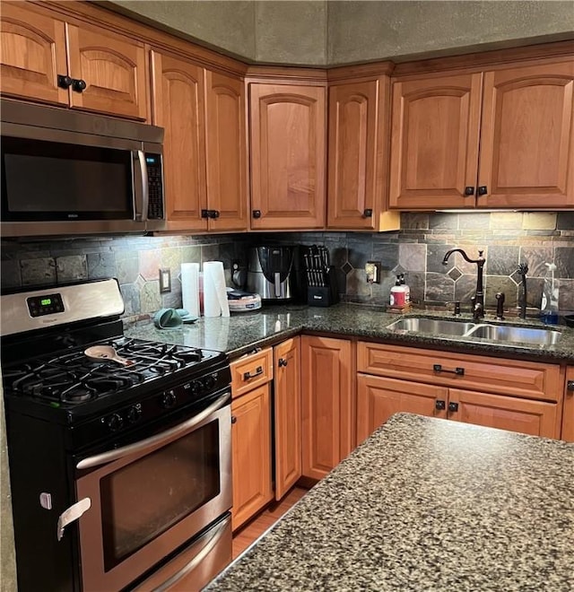 kitchen featuring tasteful backsplash, appliances with stainless steel finishes, sink, and dark stone counters