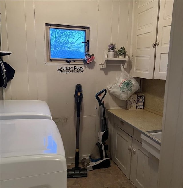 clothes washing area featuring washer and clothes dryer and cabinets