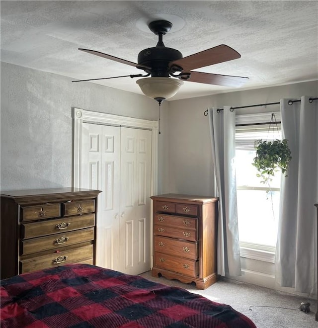 unfurnished bedroom featuring a textured ceiling, a closet, light colored carpet, and ceiling fan