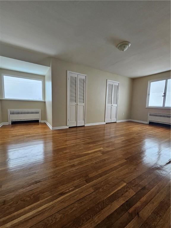 unfurnished room featuring dark hardwood / wood-style flooring and radiator heating unit