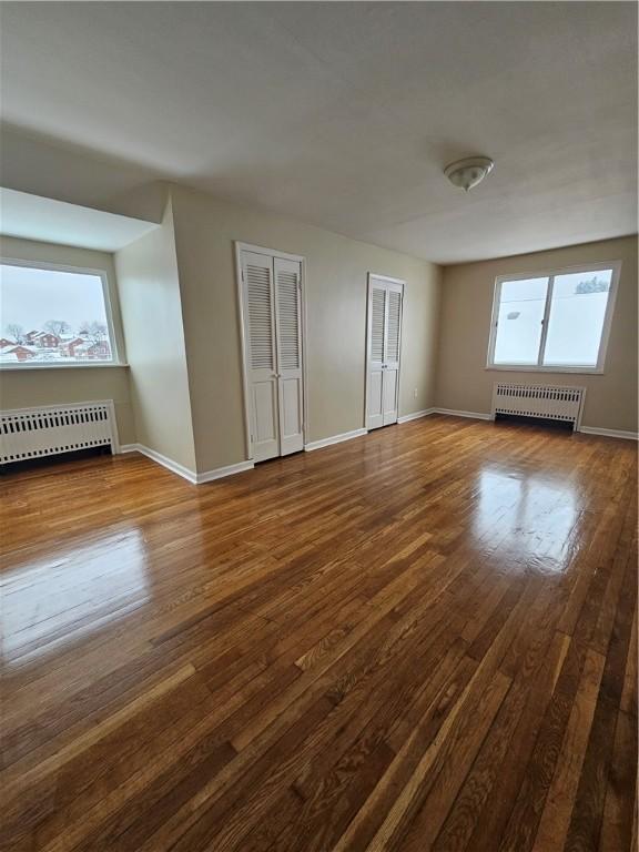 unfurnished room featuring hardwood / wood-style flooring and radiator heating unit