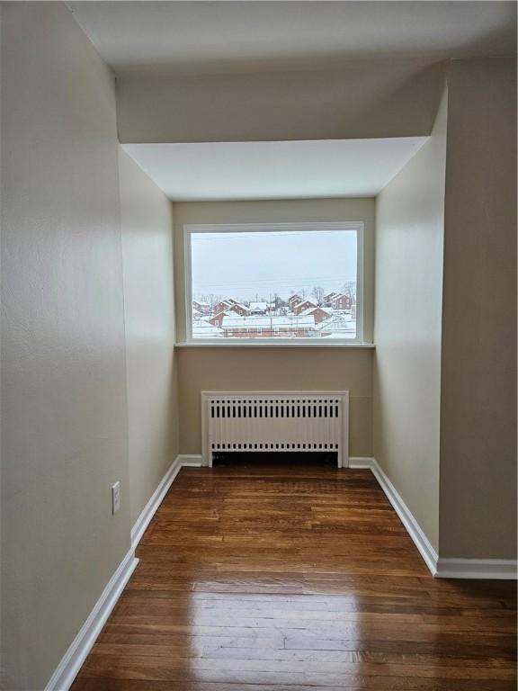 spare room featuring radiator and dark wood-type flooring