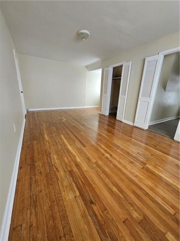 unfurnished bedroom with light hardwood / wood-style flooring and two closets