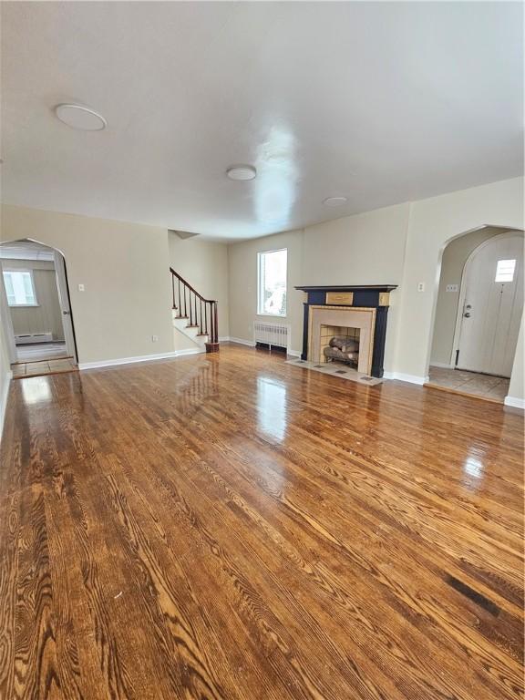 unfurnished living room featuring radiator and wood-type flooring