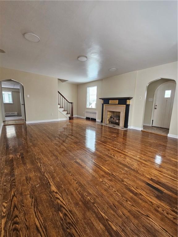 unfurnished living room featuring radiator and wood-type flooring