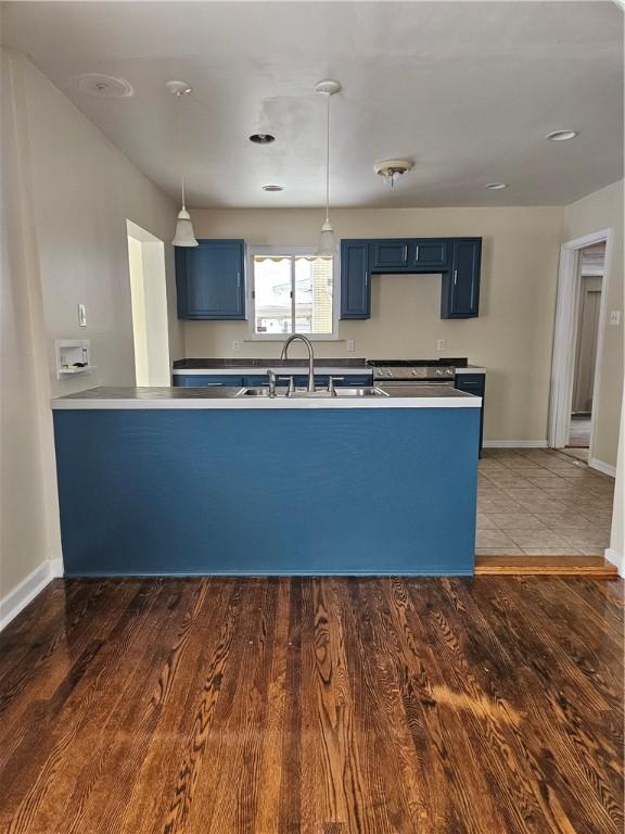 kitchen with sink, dark hardwood / wood-style floors, kitchen peninsula, and blue cabinets