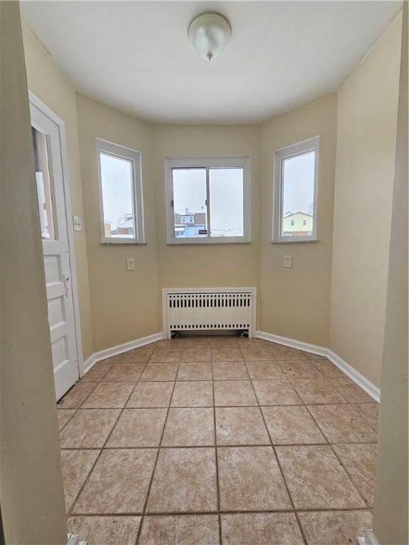 unfurnished room with radiator heating unit and light tile patterned floors