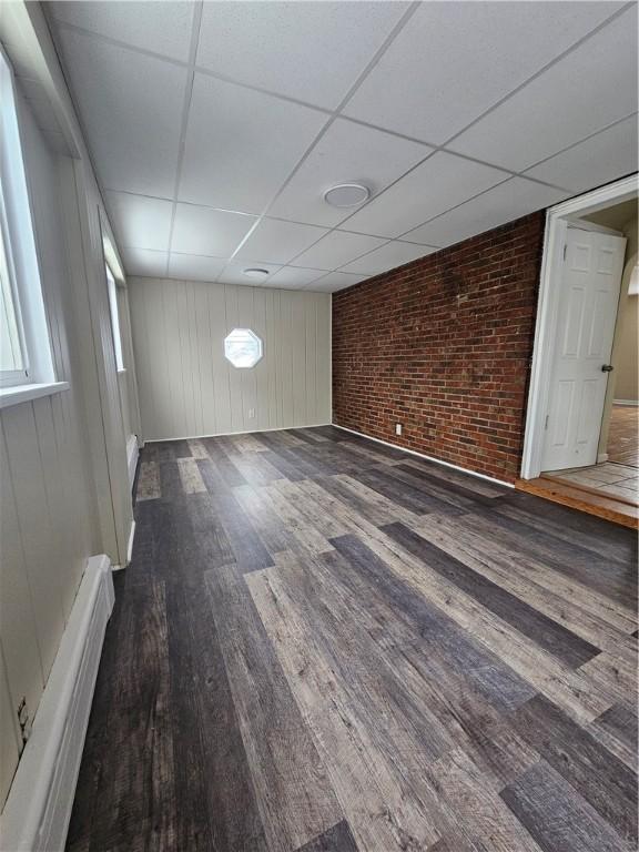 1732 Pennsylvania Ave, West Mifflin, PA 15122 - unfurnished room featuring wood finished floors, a paneled ceiling, brick wall, a baseboard radiator, and baseboards