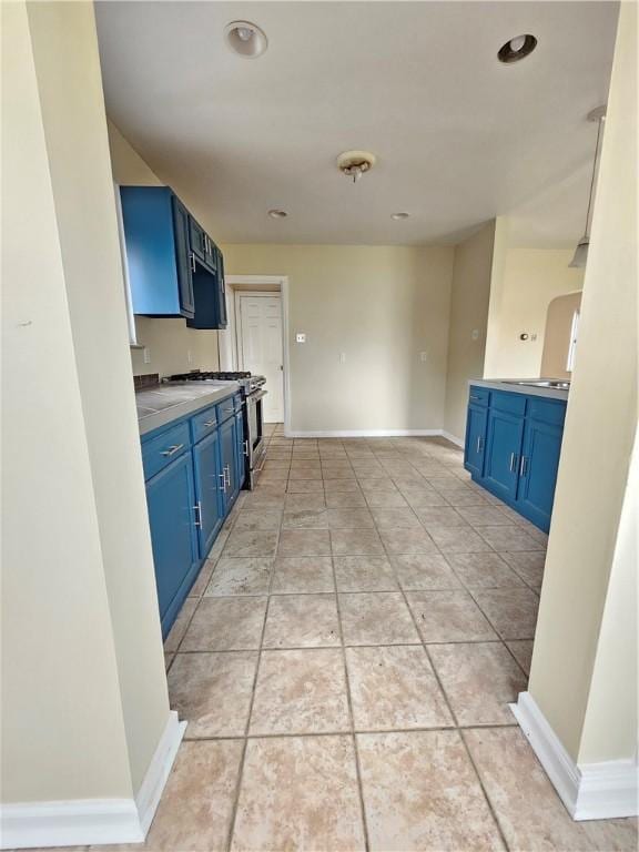 1732 Pennsylvania Ave, West Mifflin, PA 15122 - kitchen with blue cabinetry, stainless steel range with gas cooktop, baseboards, light tile patterned flooring, and recessed lighting