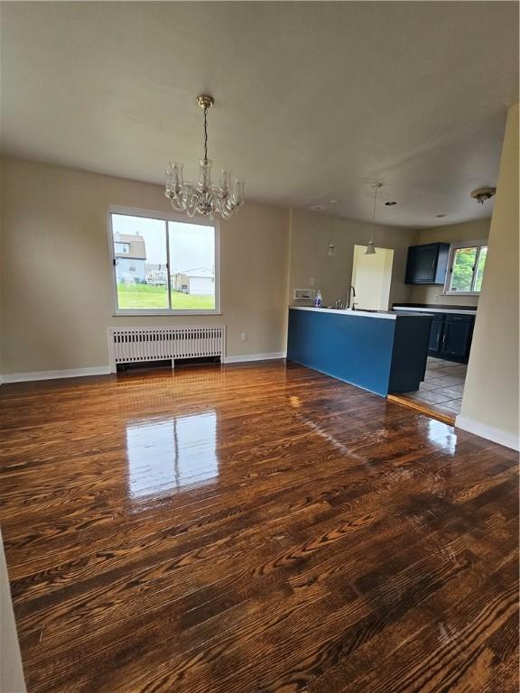 1732 Pennsylvania Ave, West Mifflin, PA 15122 - unfurnished living room featuring radiator, a chandelier, baseboards, and wood finished floors
