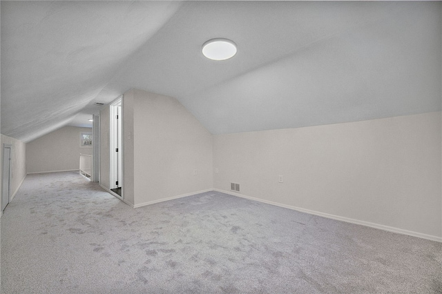 bonus room with light carpet and vaulted ceiling