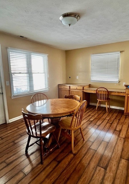 dining area featuring dark wood-type flooring and a textured ceiling