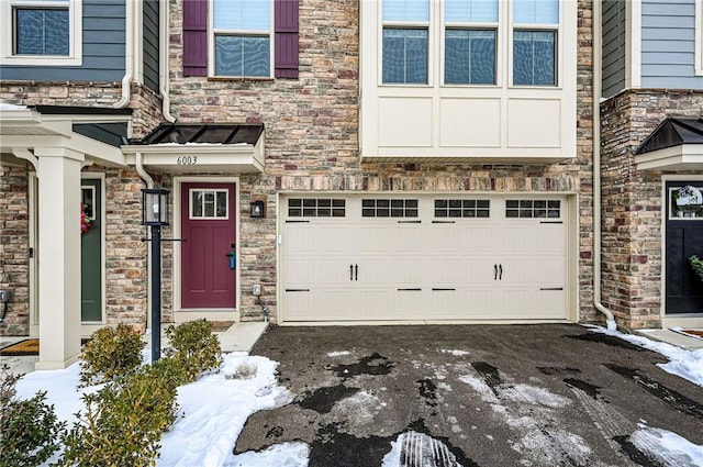 snow covered property entrance with a garage