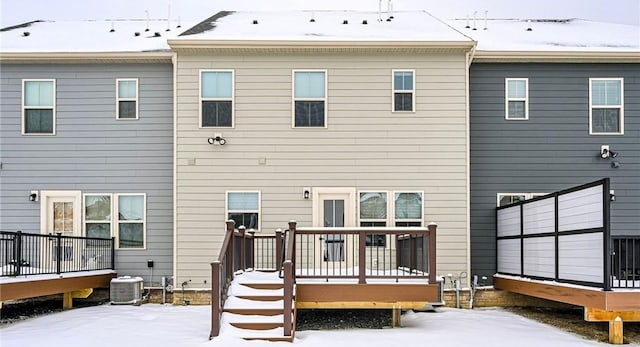 snow covered rear of property featuring a wooden deck and cooling unit