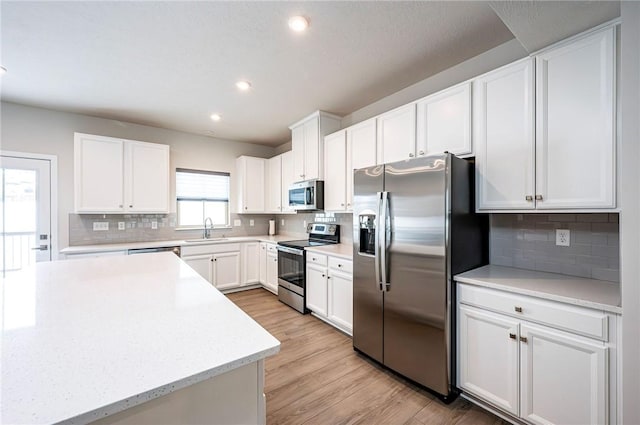 kitchen featuring backsplash, appliances with stainless steel finishes, sink, and white cabinets