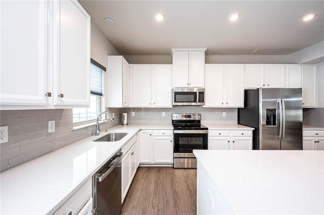 kitchen with sink, tasteful backsplash, hardwood / wood-style flooring, stainless steel appliances, and white cabinets