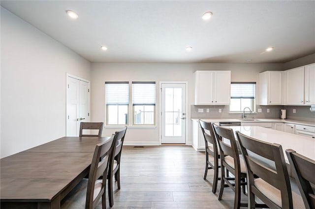 kitchen featuring sink, white cabinets, light wood-type flooring, and decorative backsplash