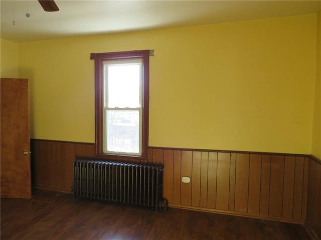 unfurnished room with ceiling fan, radiator, and dark hardwood / wood-style floors