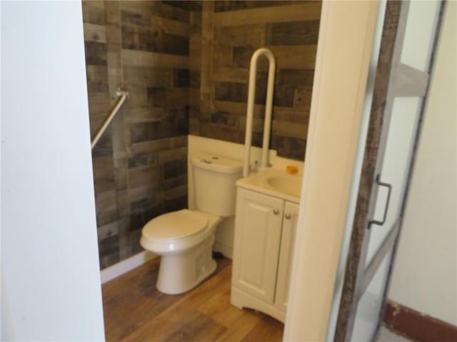 bathroom featuring wood-type flooring, walk in shower, vanity, and toilet