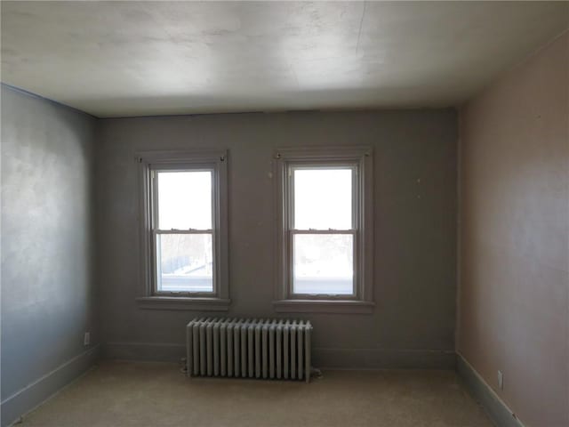 carpeted spare room featuring radiator heating unit