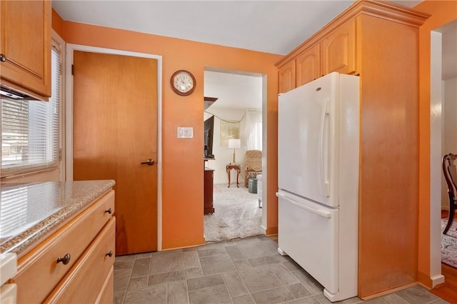 kitchen with carpet flooring, white fridge, and light brown cabinets