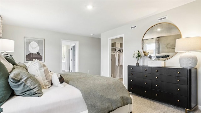 bedroom featuring light carpet, connected bathroom, a spacious closet, and a closet