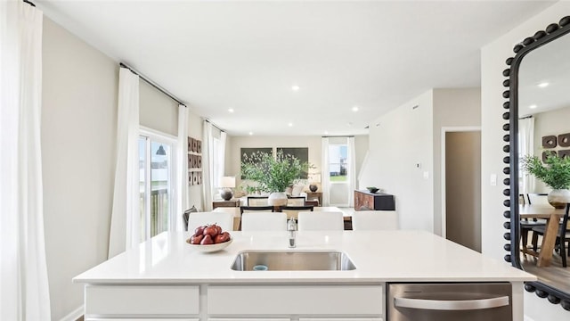 kitchen featuring sink, stainless steel dishwasher, an island with sink, and white cabinets