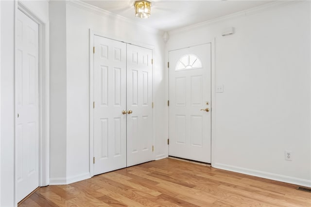 foyer entrance with ornamental molding and light hardwood / wood-style floors