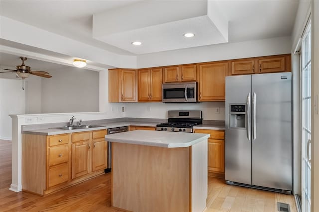 kitchen featuring sink, appliances with stainless steel finishes, a kitchen island, ceiling fan, and light hardwood / wood-style floors