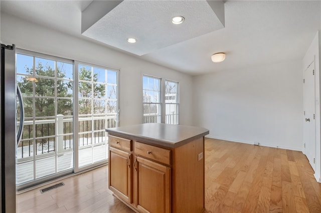 kitchen with stainless steel refrigerator, a center island, light hardwood / wood-style flooring, and a textured ceiling