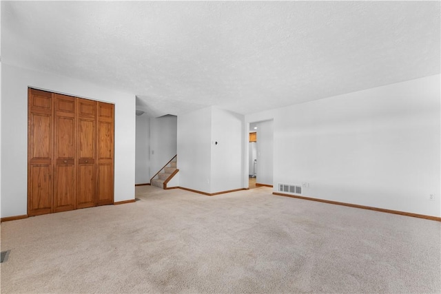 spare room with light carpet and a textured ceiling