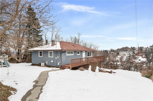 snow covered house featuring a playground and a deck