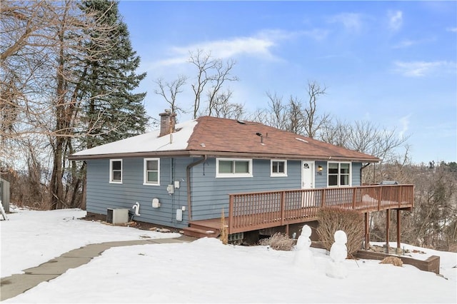 snow covered house with a wooden deck and central AC unit