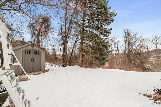 snowy yard featuring a storage unit