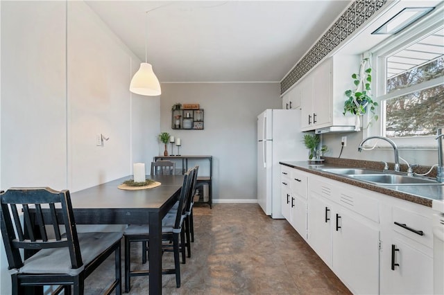 kitchen with pendant lighting, sink, white fridge, and white cabinets