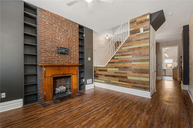 unfurnished living room with built in shelves, a fireplace, ceiling fan, and hardwood / wood-style flooring