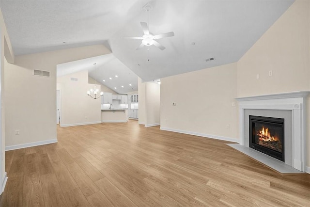 unfurnished living room featuring lofted ceiling, light hardwood / wood-style floors, and ceiling fan with notable chandelier