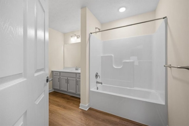 bathroom with vanity, wood-type flooring,  shower combination, and a textured ceiling